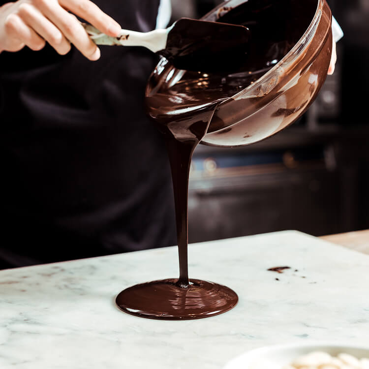 Chocolate being poured from a ladle onto a marble surface
