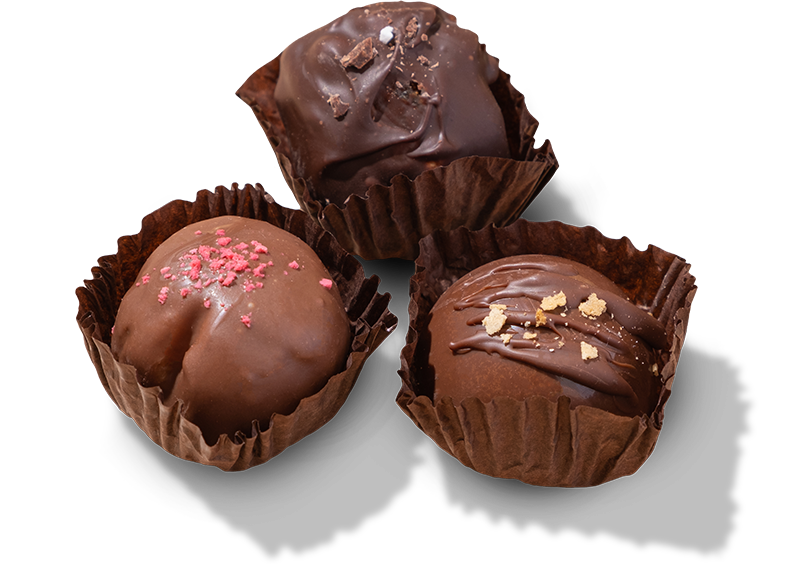 Three chocolate truffles with decorative toppings on a white background