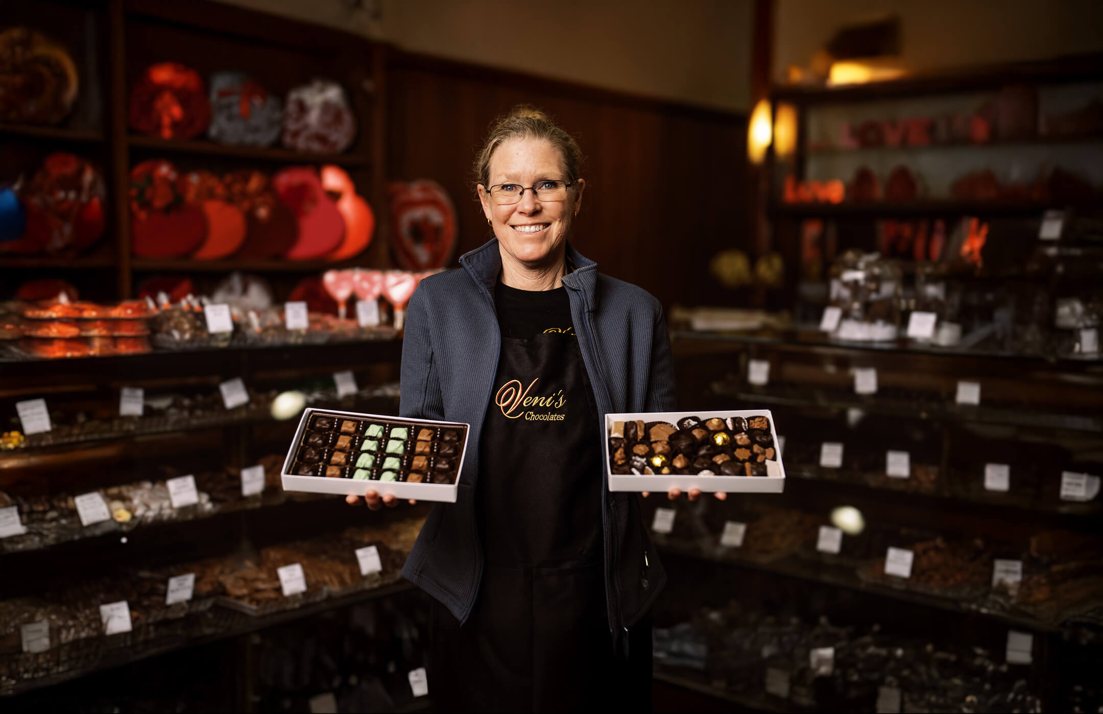 Person holding two trays of chocolates in a chocolate shop