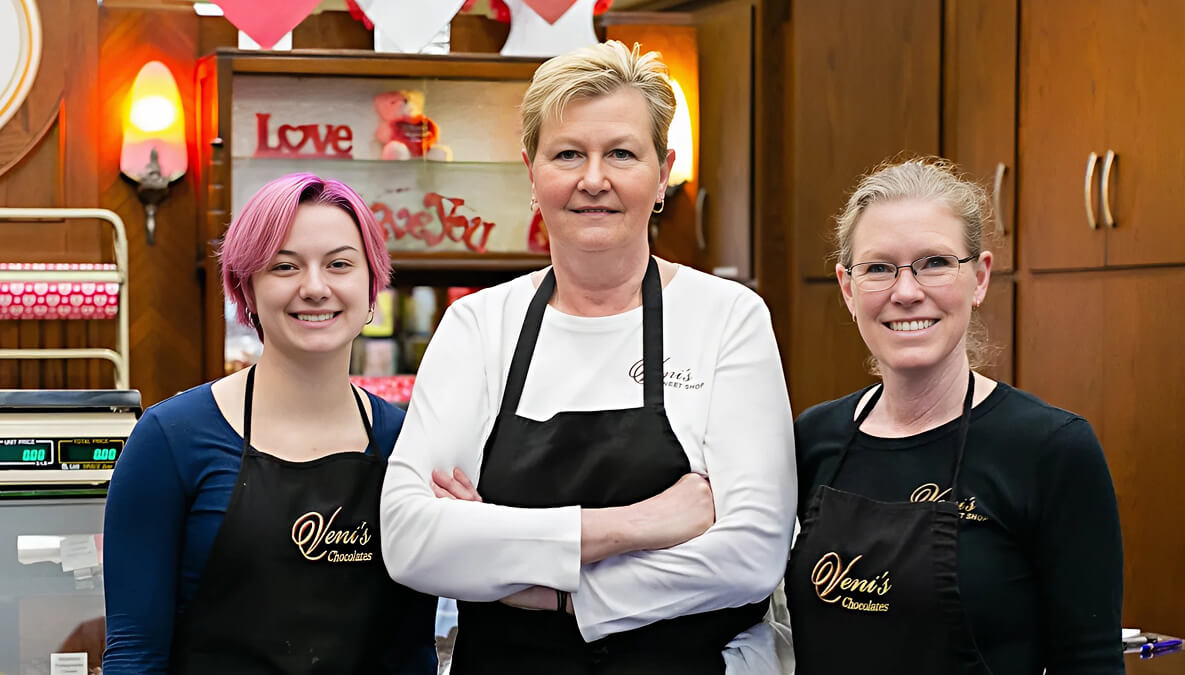 Three women wearing aprons in Veni's Sweet Shop.