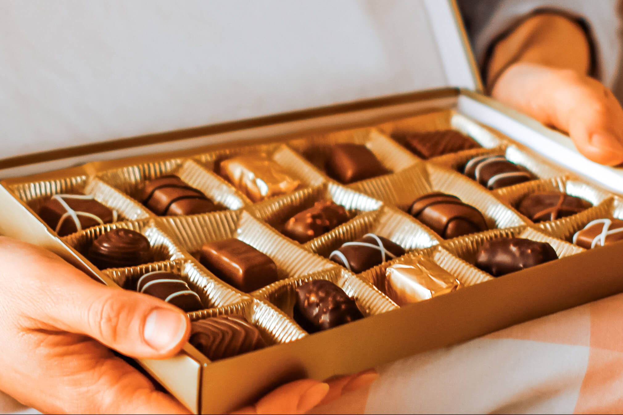 Box of chocolates held by a person with a neutral background