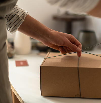 Person sealing a cardboard box with tape on a table.
