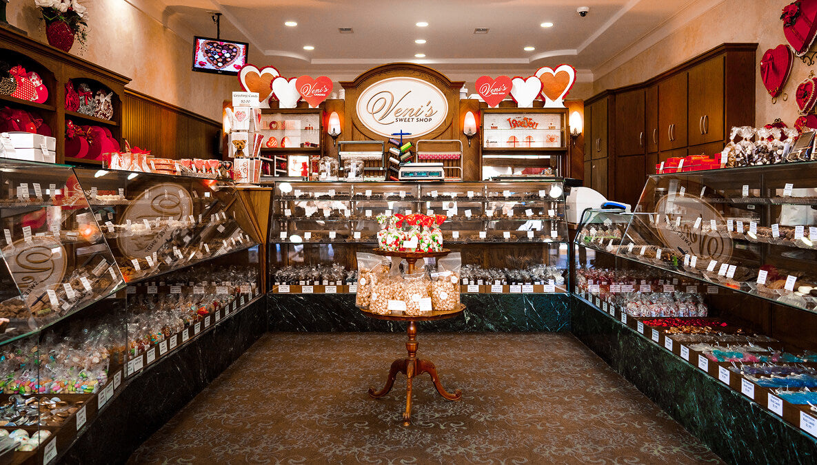 Interior of Veni's Sweet Shop with shelves stocked with various chocolate products and a central display area.