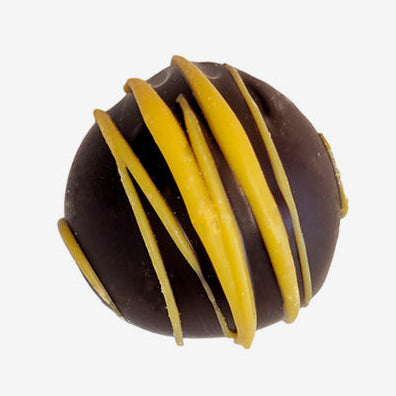 Chocolate truffle with yellow drizzle on a white background