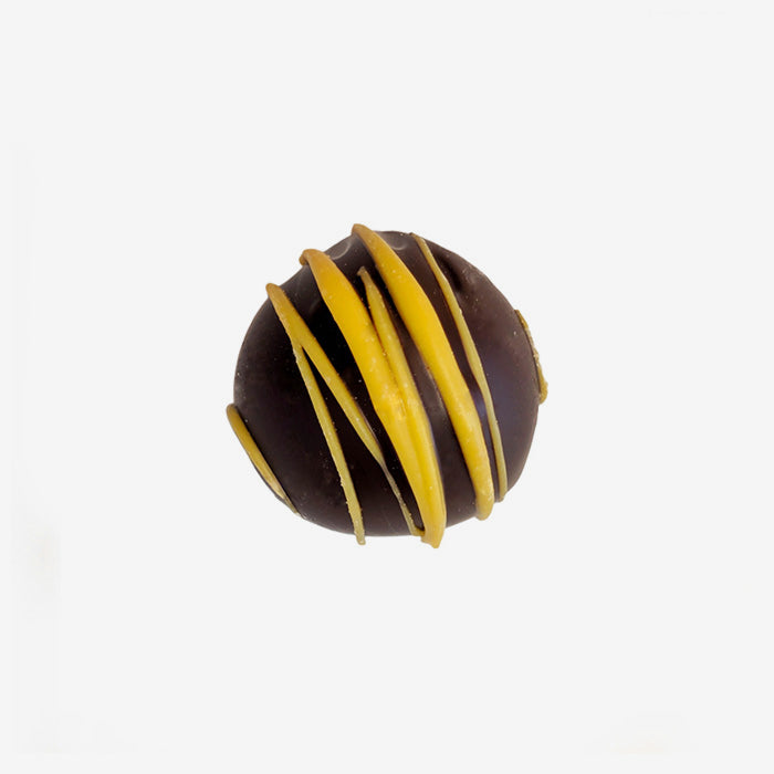 Chocolate truffle with yellow drizzle on a white background
