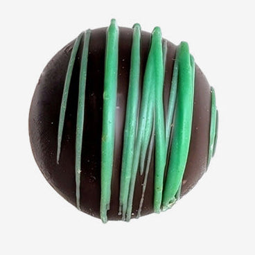 Chocolate truffle with green drizzle on a white background