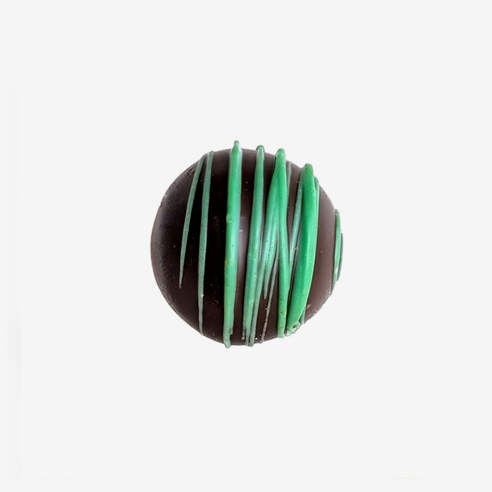 Chocolate truffle with green drizzle on a white background