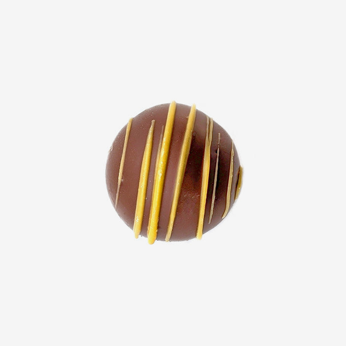 Chocolate truffle with yellow stripes on a white background