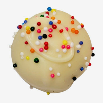 White chocolate truffle with white icing and colorful sprinkles on a white background